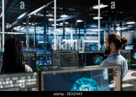 Computer scientist uses a desktop computer in a data center to manage AI systems and optimize server infrastructure. Stock Photo