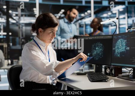 Server room worker uses a clipboard in a data center to manage AI visualization and optimize server infrastructure. Stock Photo