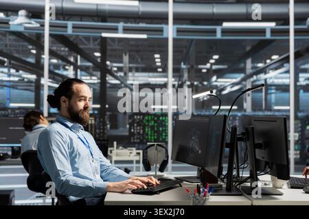System administrator uses a computer to run diagnostics, update servers and check infrastructure performance. Stock Photo