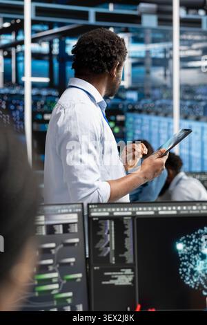 System administrator reviews AI systems and neural network parameters on a tablet inside a data center. Stock Photo