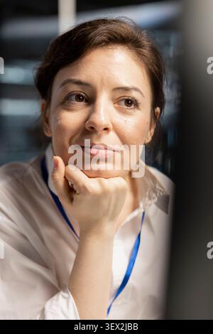 Smiling data center engineer uses a digital device to review server infrastructure, diagnostics and AI technology in a data center. Stock Photo