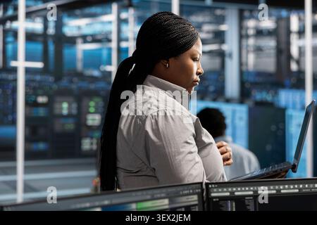 System administrator uses a laptop to run diagnostics, update servers and check infrastructure performance. Stock Photo
