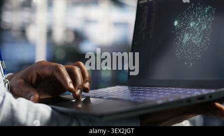 Data center technician monitors AI systems and machine learning workloads on a laptop inside a high-tech server facility. Stock Photo