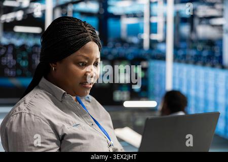 Stressed engineer panics over errors while overseeing data center machines, struggling with glitches during server rig maintenance. Stock Photo