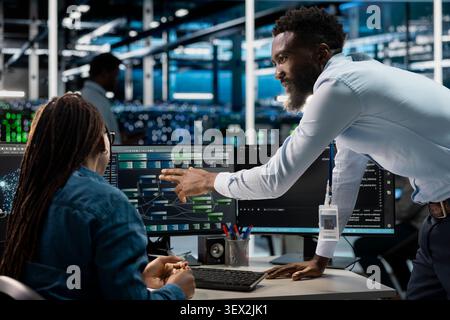 African American computer scientists set up machine learning node trees, training neural networks to improve server farm operations. Stock Photo