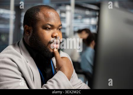 IT specialist uses a computer to run diagnostics, update servers and check infrastructure performance. Stock Photo