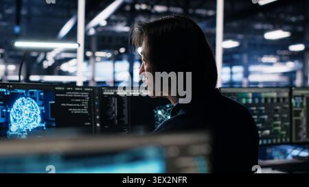 Programmer programs on a computer workstation in a server room with generative AI assistance. Stock Photo