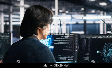 Technician programs on a computer workstation in a data center with generative AI assistance. Stock Photo