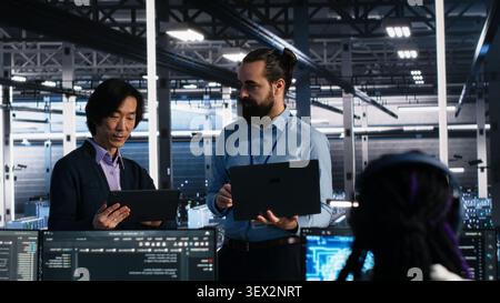 IT colleagues collaborate in a data center while reviewing AI diagnostics and infrastructure performance. Stock Photo
