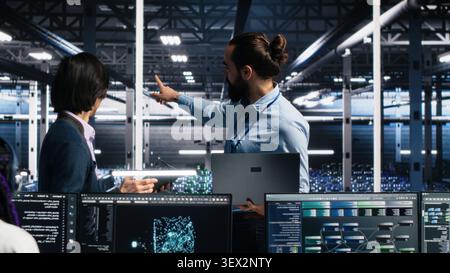 IT colleagues collaborate in a data center while reviewing AI diagnostics and infrastructure performance. Stock Photo
