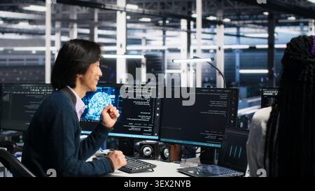 Colleagues celebrate in a server room after finishing neural network software development. Stock Photo