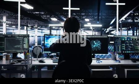 Programmer programs on a computer workstation in a server room with generative AI assistance. Stock Photo