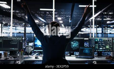 Developer celebrates in a data center after successfully programming with generative AI assistance. Stock Photo