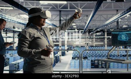 African american IT professional uses a VR headset in a server room to adjust AI systems and improve processing performance. Stock Photo