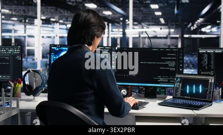 Administrator programs on a computer workstation in a high tech data center with generative AI assistance. Stock Photo