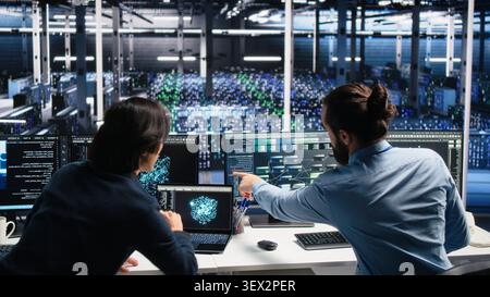 Data infrastructure center admins brainstorming, working on neural network software development, while IT staff members collaborating, implementing machine learning technology working with computer. Stock Photo