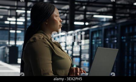 Technical specialist working with notebook computer in advanced technology server facility, integrating new technologies and systems. Stock Photo