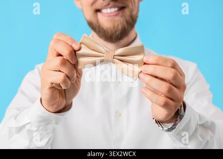 Man holding beige bow tie smiling Stock Photo