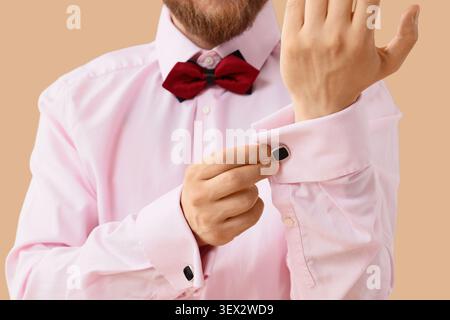 Man adjusting cufflink on pink shirt with red bow tie Stock Photo