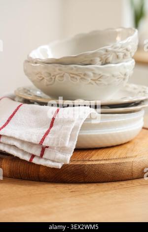 Stack of ceramic bowls and plates with kitchen towel on wooden board Stock Photo