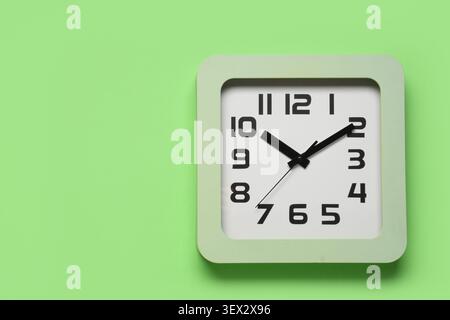 Square wall clock on green background Stock Photo