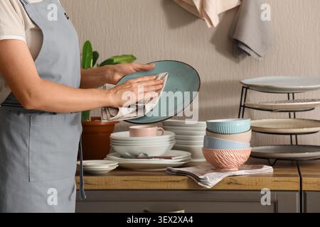 Person drying a blue plate in kitchen Stock Photo