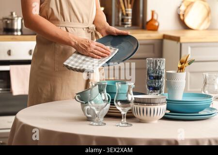 Person drying dishes in kitchen with cloth Stock Photo