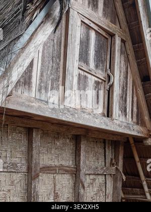 Close-up vertical shot of a weathered wooden door and woven bamboo wall of a traditional Sundanese Leuit (rice barn) in Kasepuhan Ciptamulya, Sukabumi Stock Photo