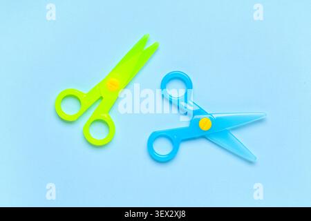 Blue and green plastic scissors on blue background Stock Photo