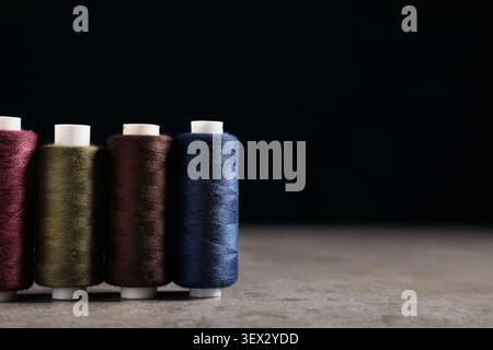 Tailors thread spools on grunge grey table against black background Stock Photo