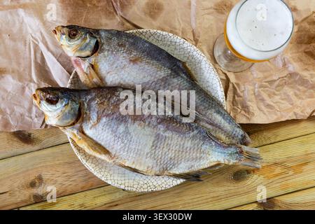 Dried bream lies on plate with imitation of antiquity. Fish complemented by glass of beer Stock Photo
