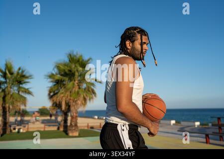 Young man holding basketball on outdoor court Stock Photo