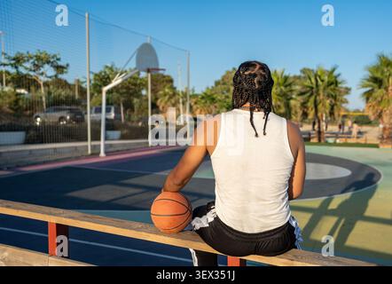 Young black man relaxing on basketball court Stock Photo