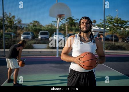 Male basketball player holding ball on urban court Stock Photo