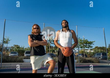 Diverse men posing on outdoor basketball court Stock Photo
