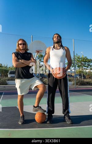 Diverse men posing on outdoor basketball court Stock Photo