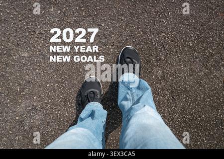 Top view of woman wearing sport shoes with message, 2027 New Year New Goals. Stock Photo