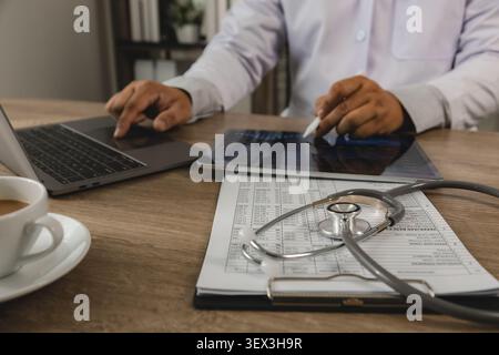 Healthcare business intelligence professional analyzing data dashboard on tablet and laptop with medical records. KPI monitoring, healthcare analytics Stock Photo