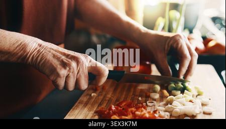 Mature, hands and cutting with vegetables in kitchen for meal prep, cooking or healthy food. Person, knife and organic ingredients with culinary skill Stock Photo