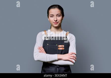 Confident young female in apron looking at camera Stock Photo