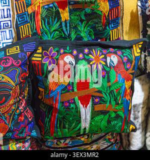 Guatemalan cushion cover with embroidered macaw parrots and a central quetzal bird. Mayan home decor textile. Stock Photo