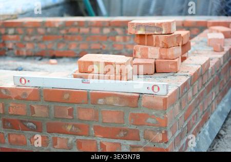 Construction Worker Checking Brick Wall Level During Masonry Stock Photo