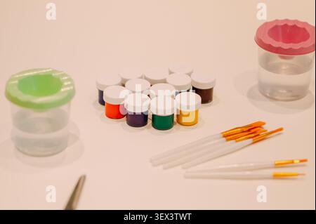 Paint brushes, colorful acrylic paints and water cups for art workshop Stock Photo