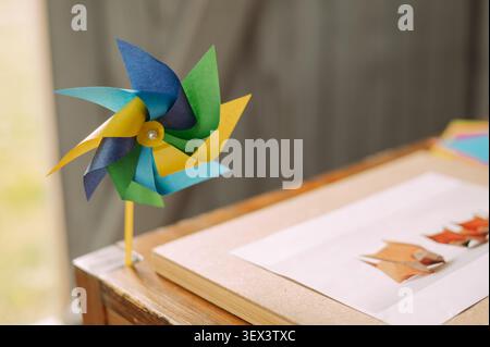 Colorful paper pinwheel on wooden table with origami craft in classroom Stock Photo