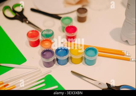 Colorful paint pots with art supplies on white table for creative activities Stock Photo