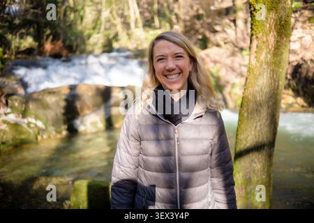 Young woman smiling, enjoying healthy outdoor adventure in natural forest setting Stock Photo