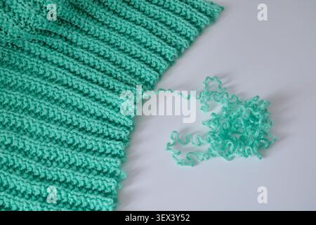 Mint green yarn unraveling from a ribbed knit fabric Stock Photo