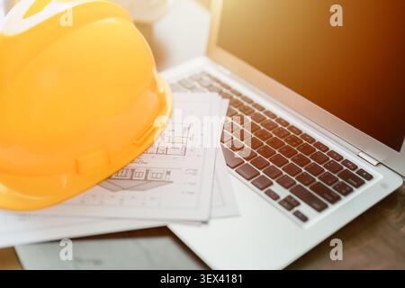 Construction Engineer Safety Helmets on Laptop Computer Architect Office Desk, Home Construction Engineers Project Design. Stock Photo