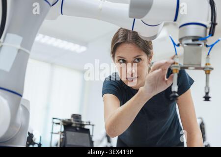 Young engineer woman working in Robotic lab test and program robot prototype. Robotic factory research. Automation robot arm. Stock Photo