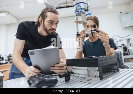 Young engineer team working in Robotic lab test and program robot prototype. Robotic factory research. Automation robot arm. Stock Photo